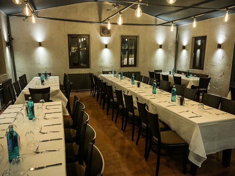 Lange, weiß eingedeckte Tafeln im Saal, darüber Glühbirnen an der Decke